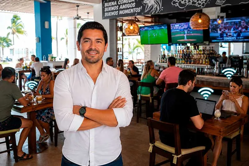 Dueño de un restaurante con sus clientes conectados al WiFi y el futbol en las pantallas