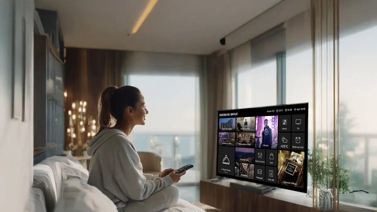Huésped usando la TV interactiva de su habitación, con vista al mar